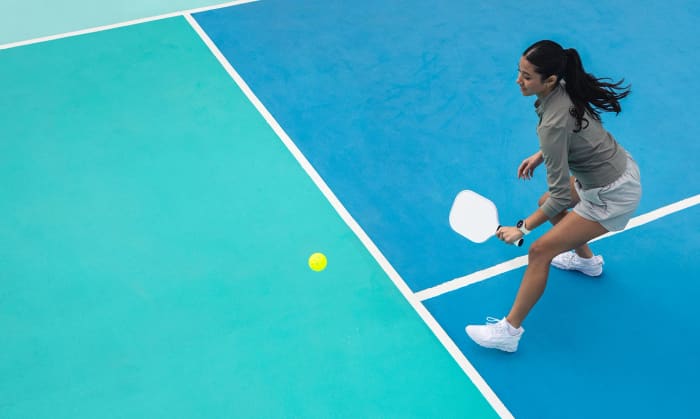 A woman playing pickleball wearing a Garmin vívoactive 6