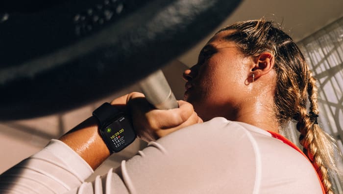 A woman lifting weights wearing an Apple Watch Series 12